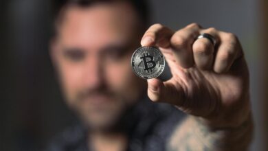 Adult male hand holding a Bitcoin, showcasing cryptocurrency focus indoors.