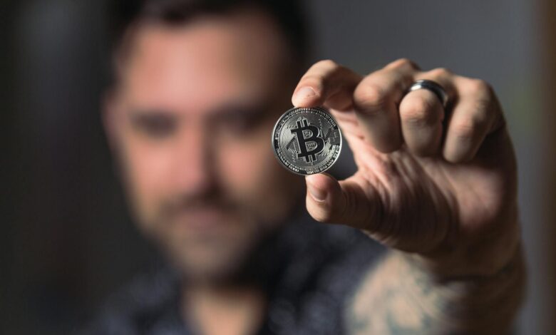 Adult male hand holding a Bitcoin, showcasing cryptocurrency focus indoors.