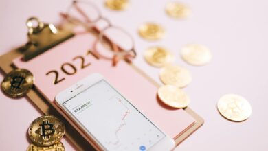 Close-up of a smartphone with crypto chart, bitcoin coins, and 2021 notepad.