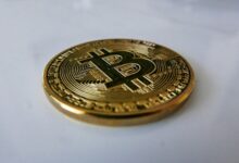 a gold bit coin sitting on top of a white table