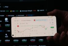 A person holding a business card in front of a computer screen